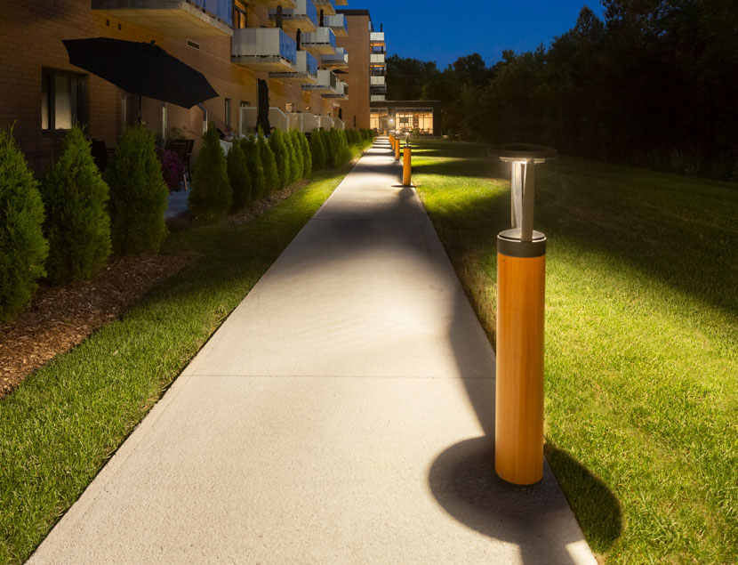 Maya bollards illuminate pathway outside apartment building